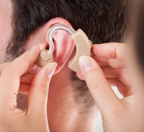 Close-up,Of,Hand,Helping,Young,Man,To,Wear,Hearing,Aid